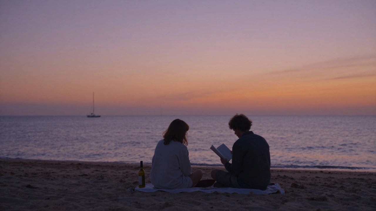 Two people sitting together on a beach at sunset, relaxed and engaged in quiet conversation.